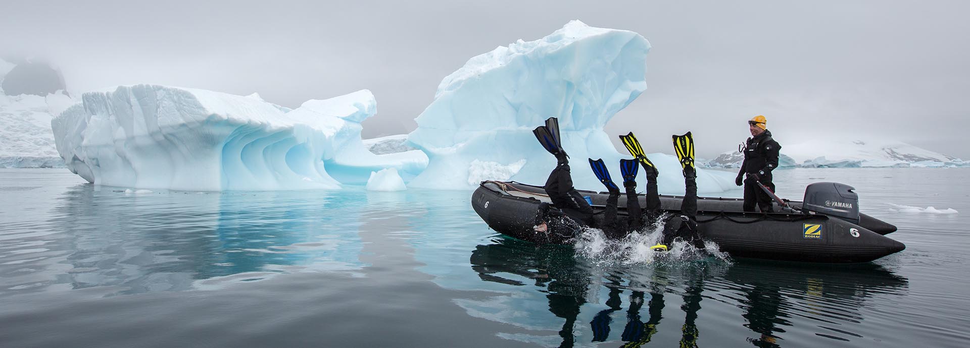 Divers taking the plunge between icebergs in Antarctica