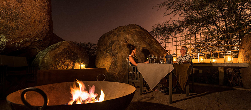 Couple enjoys an intimate, romantic dinner next to a firepit at a private safari suite in Namibia
