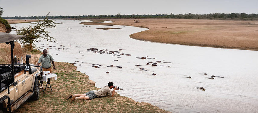 Guest photographing hippos on a luxury safari in South Luangwa National Park, Zambia