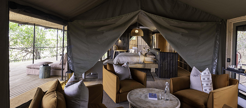 Interior of a family tent at Kiri Camp showcasing a relaxed lounge area and spacious sleeping quarters.