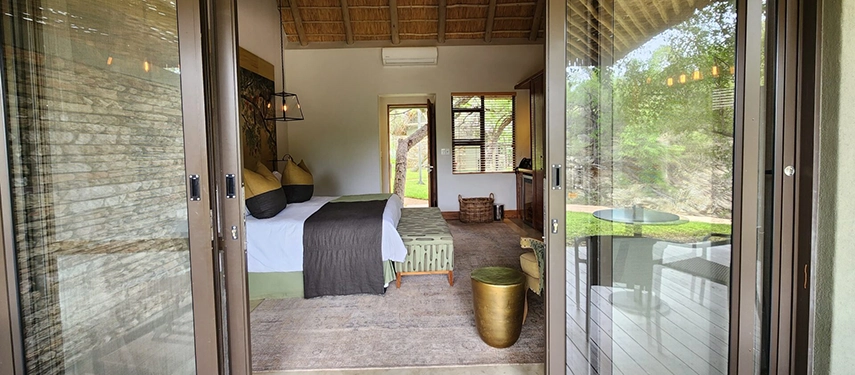 A luxury suite at Simbavati Camp George opens onto a private deck, offering generous space and views into the surrounding bush.