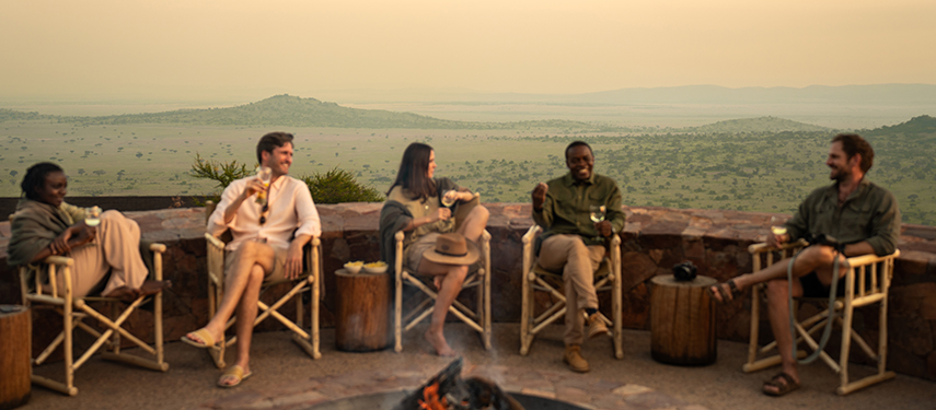 Group enjoying sundowners around a campfire boma on the Serengeti, Tanzania