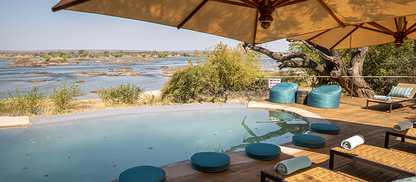 Tranquil riverside pool deck at Toka Leya with loungers and shade umbrellas