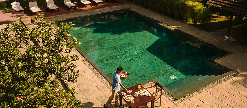 Swimming pool surrounded by trees at a luxurious colonial-style hotel in Sri Lanka