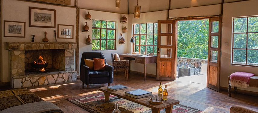 An inviting sitting area at Volcanoes Bwindi Lodge opening onto a forest-facing terrace, blending indoor comfort with the sights and sounds of Bwindi.