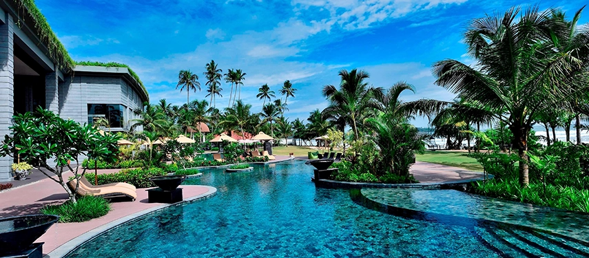 The lagoon-style pool at Weligama Bay Marriott Resort & Spa surrounded by tropical gardens, swaying palms, and views towards the beach.