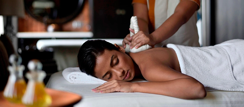 A relaxing spa treatment at Weligama Bay Marriott Resort & Spa with a therapist applying a herbal compress as the guest unwinds peacefully.