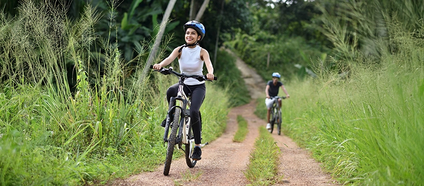 Cyclists ride along a peaceful dirt path bordered by tall grass near Weligama Bay Marriott Resort & Spa.
