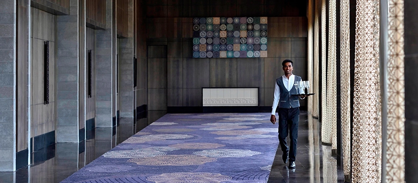 A smartly dressed server carries drinks through an elegant corridor of Weligama Bay Marriott Resort & Spa.