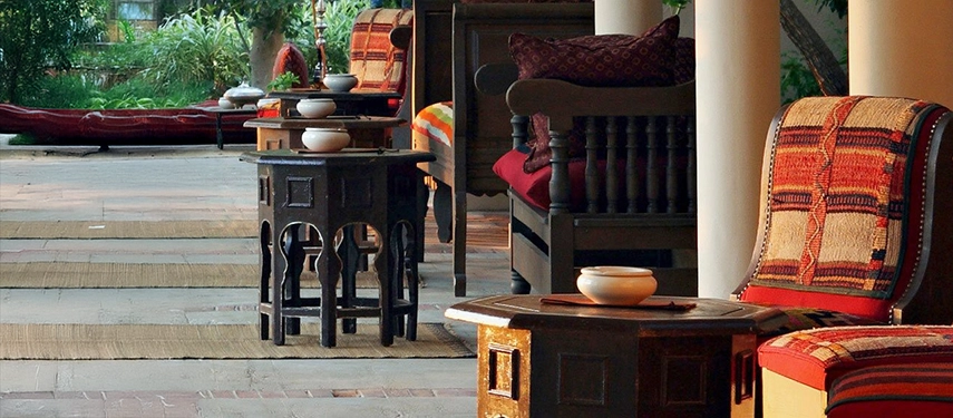 Outdoor terrace with traditional Tunisian furniture and patterned textiles, surrounded by lush greenery.