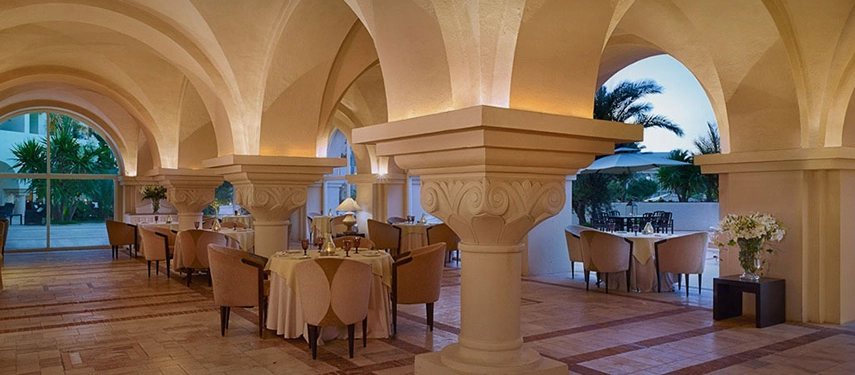 Refined dining setup under grand arches at The Residence Tunis restaurant in Tunisia, blending elegance with Mediterranean warmth.