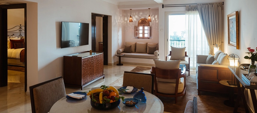 Spacious suite with dining area, plush seating, and a balcony with partial sea views at a luxury Tunisian resort.