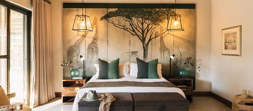 A beautifully styled en suite bedroom at Simbavati Camp George features safari-inspired artwork, soft lighting, and calm bush-facing views.