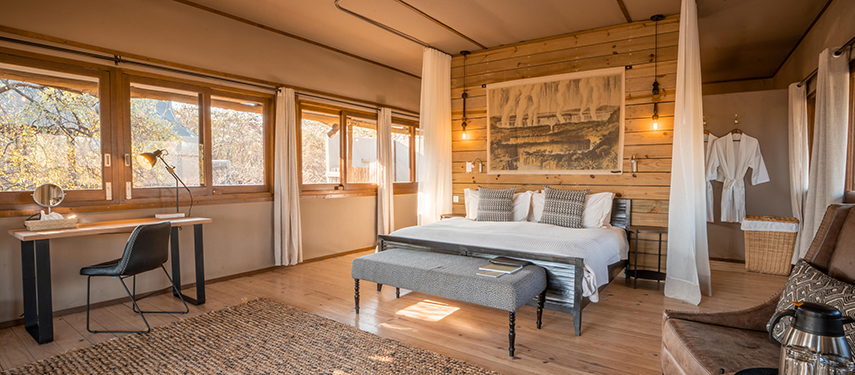 Sunlit interior of a luxury tent at Toka Leya with large windows and desk
