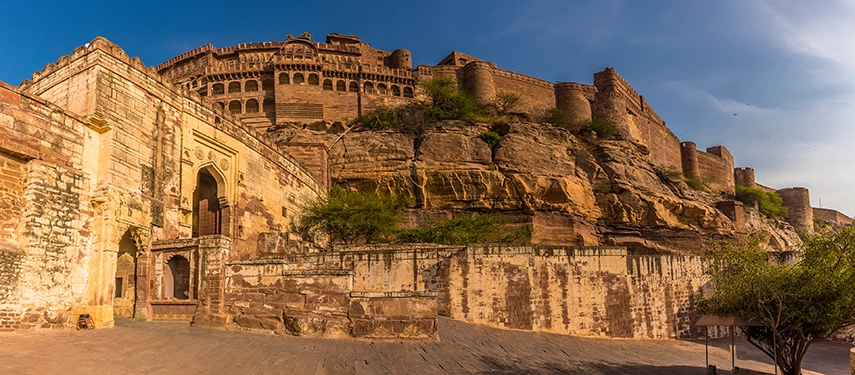 Imposing Mehrangarh Fort perched atop rocky cliffs in Jodhpur, bathed in warm afternoon light. 