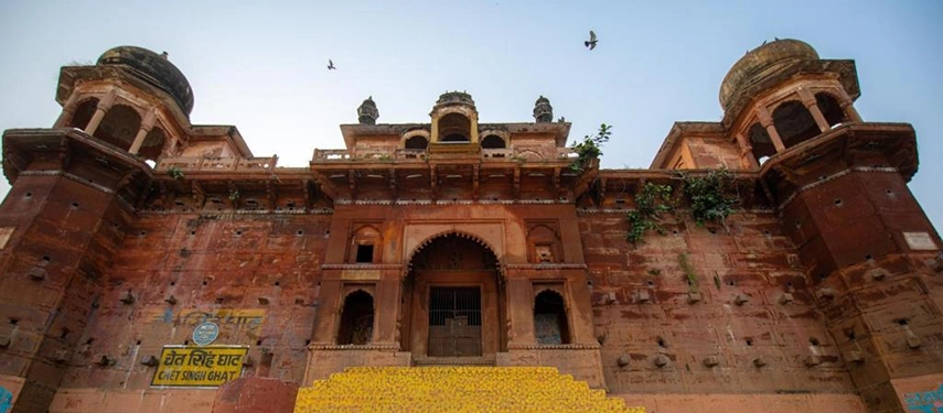 Facade of the historic Chet Singh Ghat with grand arched entrance and yellow stone steps leading to the river.