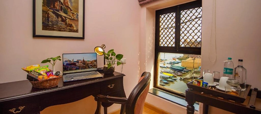 Work desk setup beside a window overlooking the colourful ghats and boats on the Ganges River.