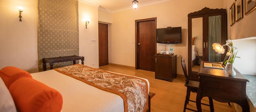 Spacious double room with warm lighting, traditional furnishings, and a writing desk by the window.