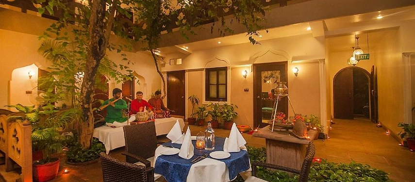 Evening courtyard dining with live musicians performing beside candlelit tables and leafy plants.