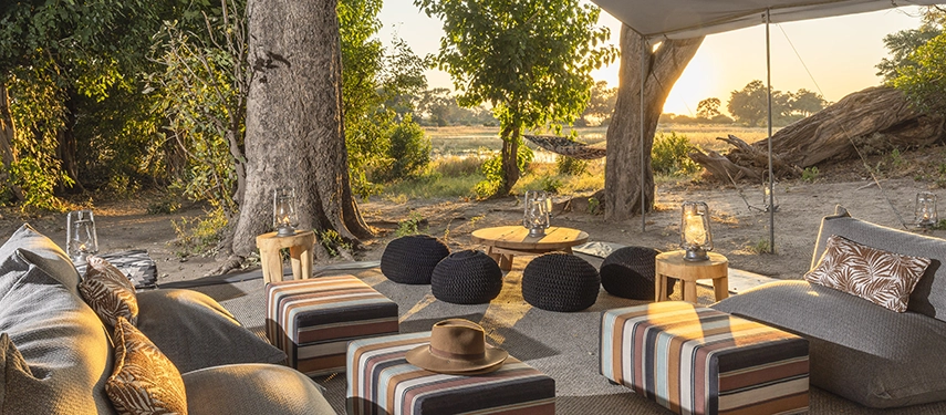 Stylish lounge area with striped ottomans, soft seating, and lanterns beneath canvas overlooking Delta views.