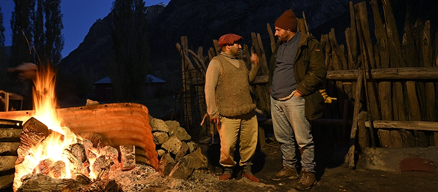 Two men talking beside a roaring fire in the outdoor corral at Estancia El Cóndor.
