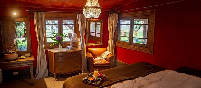 Warmly lit guest room with rustic wooden décor and leather armchair at Estancia Don Joaquín.