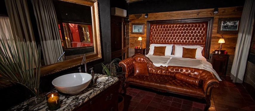 Elegant guest room with tufted leather headboard, marble basin, and warm lighting at Estancia Don Joaquín.