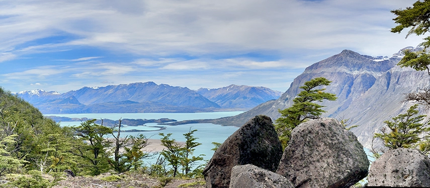 Scenic view of turquoise Lago San Martín framed by rocky outcrops and forested slopes.