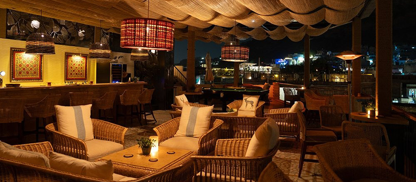 Atmospheric rooftop bar at The Stepwell House glowing under the night sky.