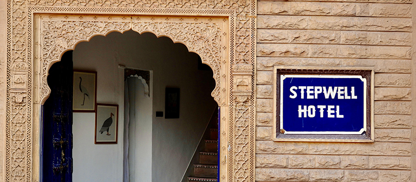 Traditional entrance to The Stepwell House with intricate stonework and blue signage.