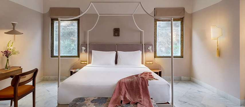 Minimalist guestroom with canopy bed, marble floors, and soft lighting
