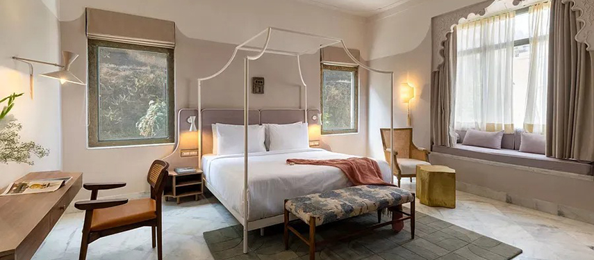 Elegant heritage guestroom with canopy bed, marble flooring, and arched window seating