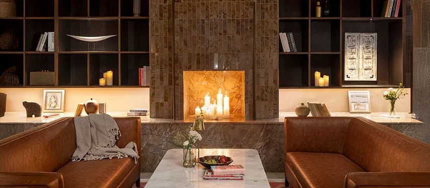 Cosy library-lounge area with leather sofas, lit fireplace, and built-in bookcases – Jhilwara Haveli