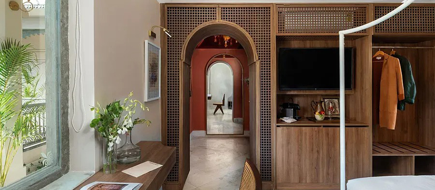 View from guestroom showing open wardrobe, arched doorway, and decorative detailing