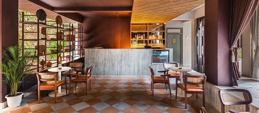 Indoor café area with chequered flooring, marble bar, and rattan furniture