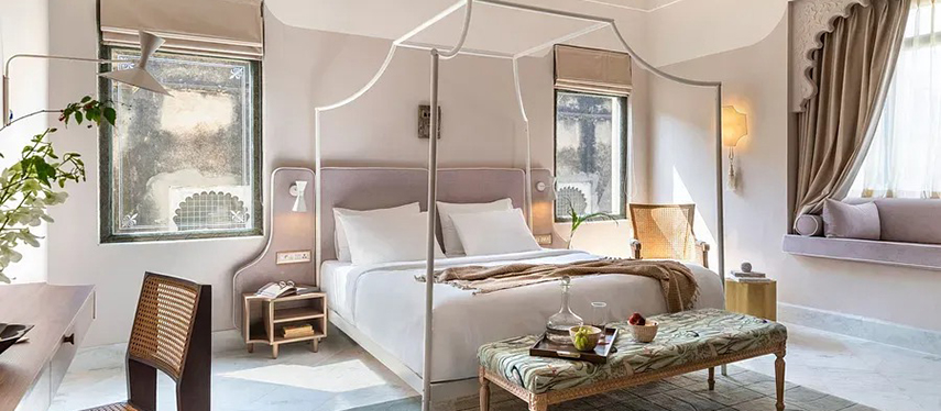 Boutique-style guestroom with arched windows, elegant canopy bed, and garden views