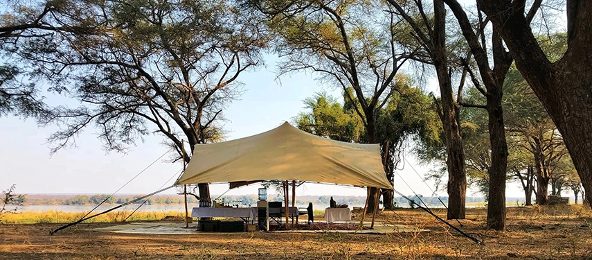 Large canvas shade canopy with chairs and tables set for al fresco dining at Kutali Camp.