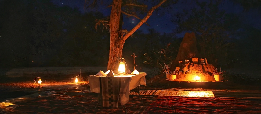 Romantic lantern-lit dinner set under the stars at Kutali Camp with warm firelight.
