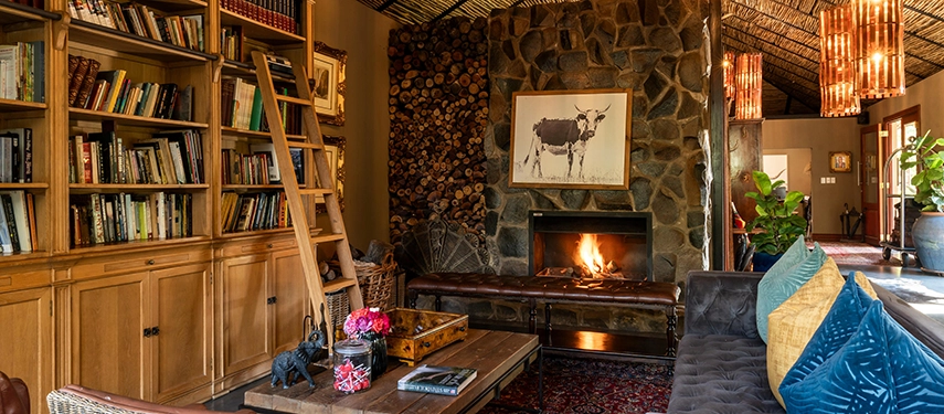 The library lounge at Mukwa River Lodge combines stone fireplaces, bookshelves, and comfortable seating in a warm, inviting indoor retreat.