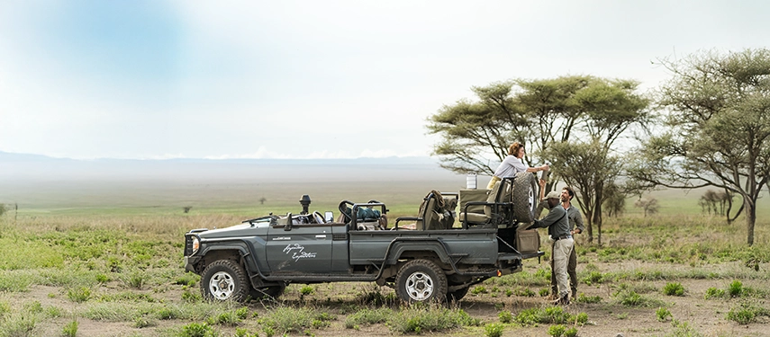 A guided safari vehicle pauses on the plains for a relaxed picnic lunch, capturing the freedom and scale of game drives around Nyasi Tented Camp.