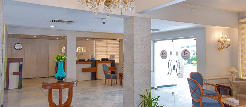 The bright marble-floored lobby of Obelisk Nile Hotel with soft seating, chandeliers and a welcoming reception desk.
