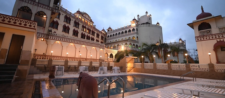 An exterior evening view of Padmaa Haveli featuring a pool, domed rooftops, and warm lighting.