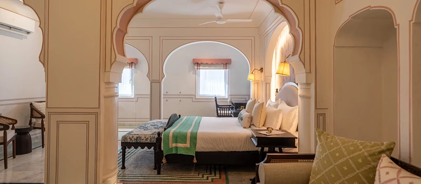 A serene suite at Padmaa Haveli with carved arches, neutral tones, and traditional Rajasthani furnishings.