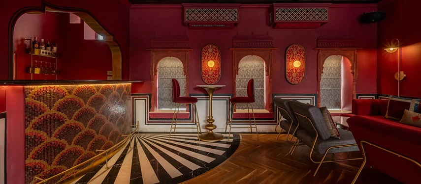 A vibrant lounge at Padmaa Haveli featuring bold red walls, arched alcoves, and patterned bar mosaic tiles.
