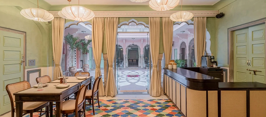 A cheerful dining space at Padmaa Haveli overlooking the inner courtyard, with pastel walls and colourful tiled flooring.