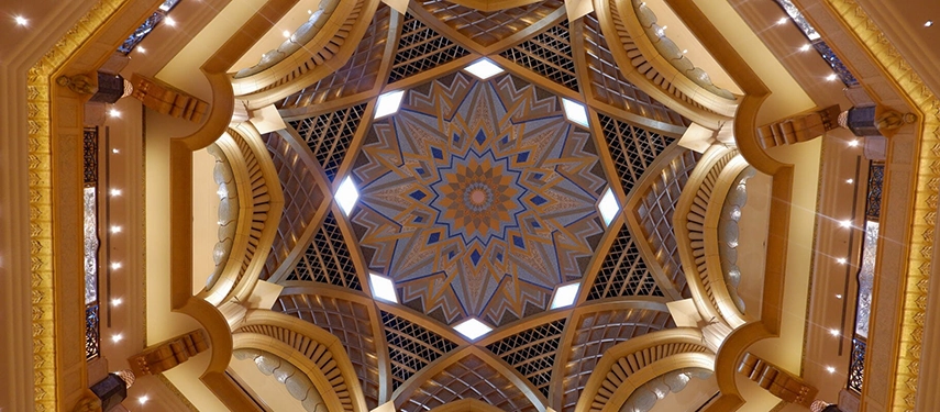 An ornate star-patterned ceiling with golden pillars and symmetrical geometry, viewed from directly beneath.