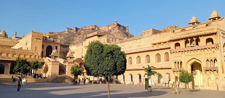 A wide-angle view of Amber Fort in Jaipur with its sand-coloured walls, courtyards, and backdrop of rugged hills.
