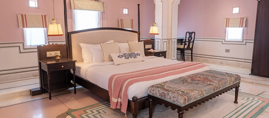 A softly lit heritage suite at Padmaa Haveli with pink walls, marble floors, and a mix of vintage furnishings.