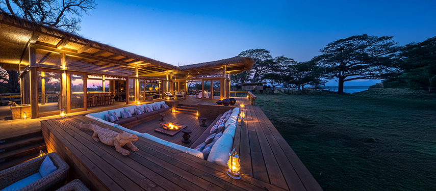 Cosy fire pit lounge surrounded by timber deck at Shumba Camp at nightfall