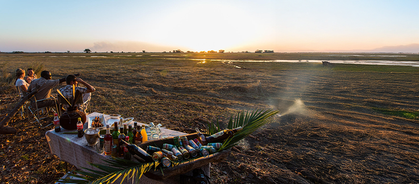 Guests enjoying sundowners at a scenic bush bar overlooking the Busanga Plains at sunset